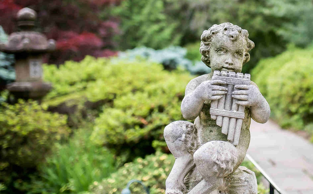 Statue of a satyr playing pipes, located by Hillwood's Japanese-style garden 