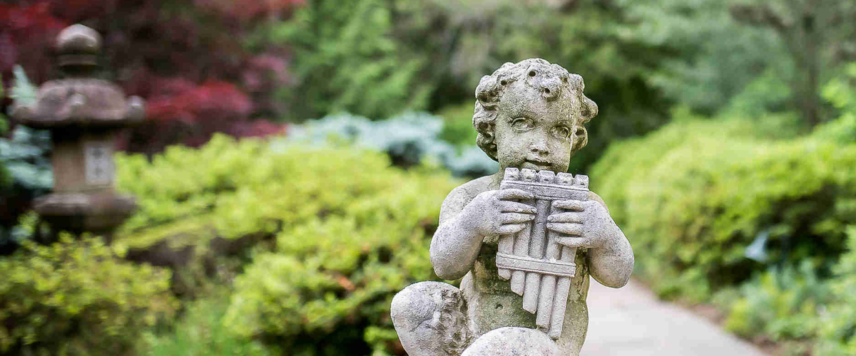 Statue of a satyr playing pipes, located by Hillwood's Japanese-style garden 