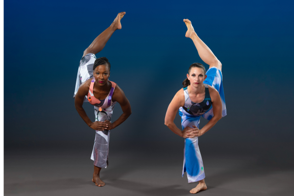 Photo of two dancers holding a pose with one leg extended.