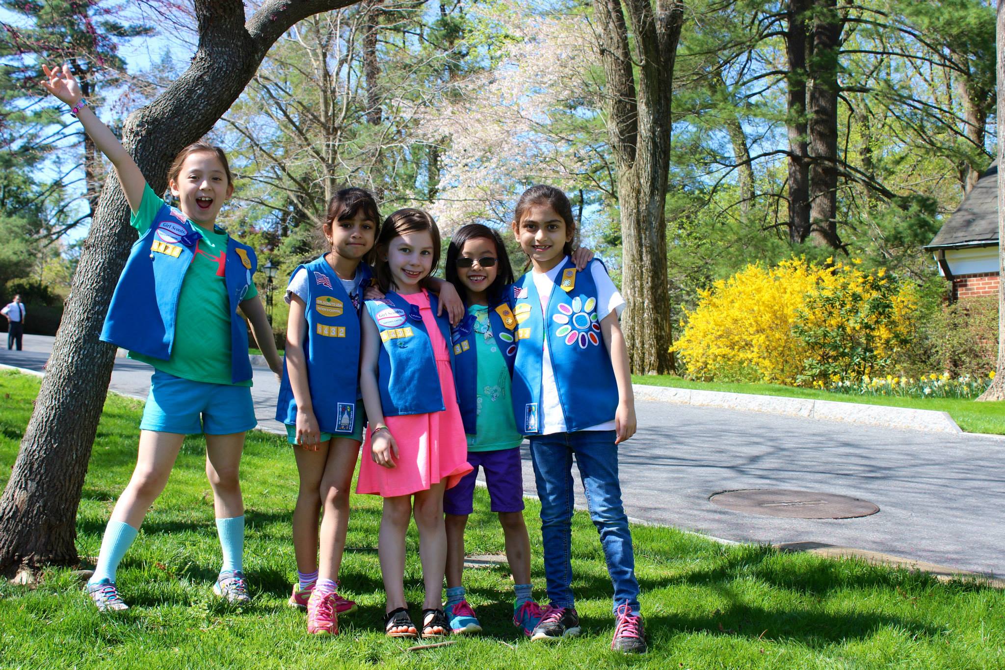 Five Daisy Girl Scouts gathered together and smiling outdoors in Hillwood's gardens