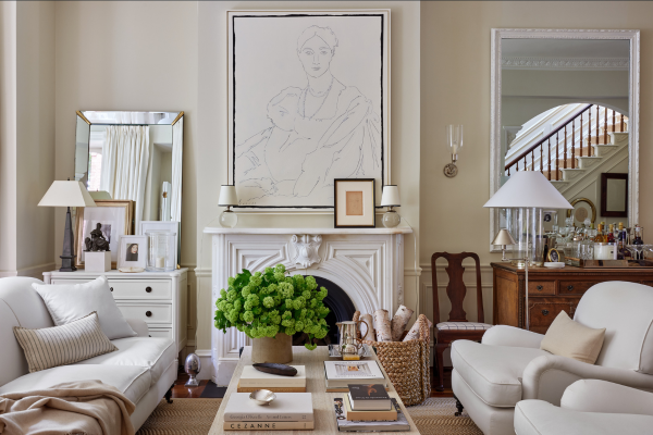 Image from the cover of "Artful Home" by Josh Young. The image features a large pencil-line portrait hanging over a white fireplace. There are white couches on the periphery of the image, with a light wooden coffee table between the couches. The coffee table features a fluffy, green house plant.