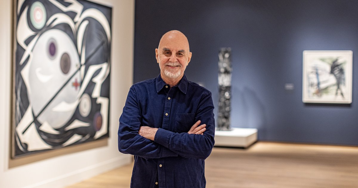 Headshot of Kenneth Silver posing in an art gallery with his arms crossed.