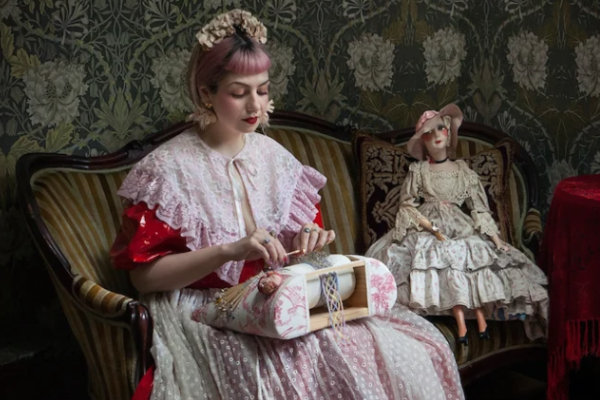 Image of Elena Kanagy-Loux creating bobbin lace while wearing an intricate lace shawl.