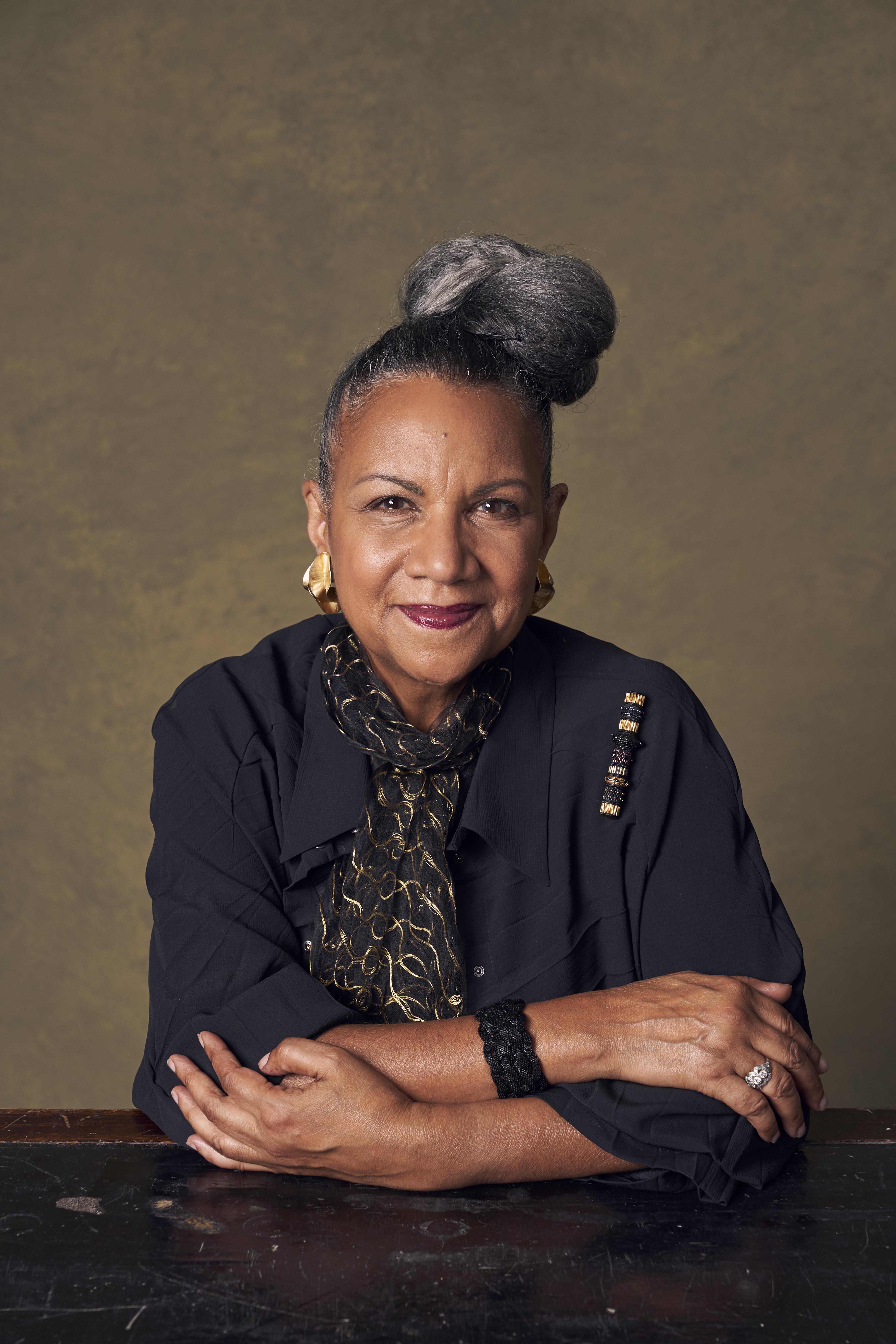 Headshot of A'Lelia Bundles. She sits with her arms crossed in front of her on a table.