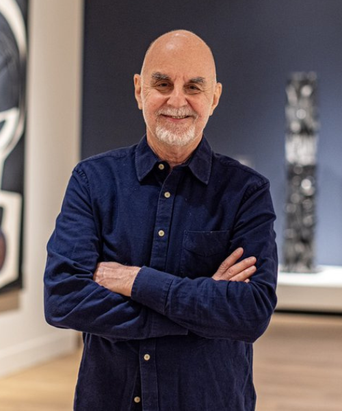 Headshot of Kenneth Silver, posing in an art gallery.