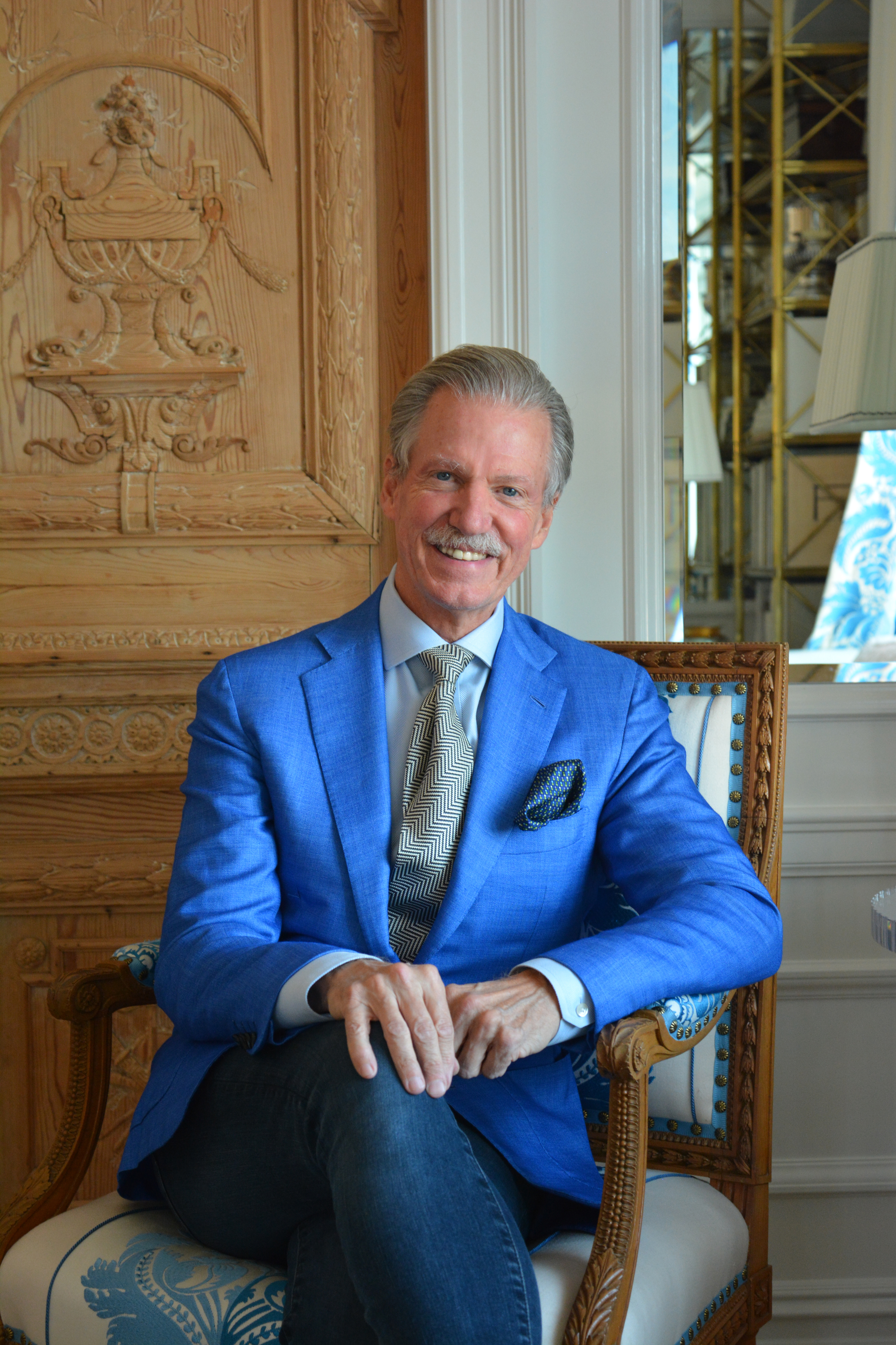 Headshot of Marshall Watson. He is wearing a light blue suit and sitting in a decorative chair.