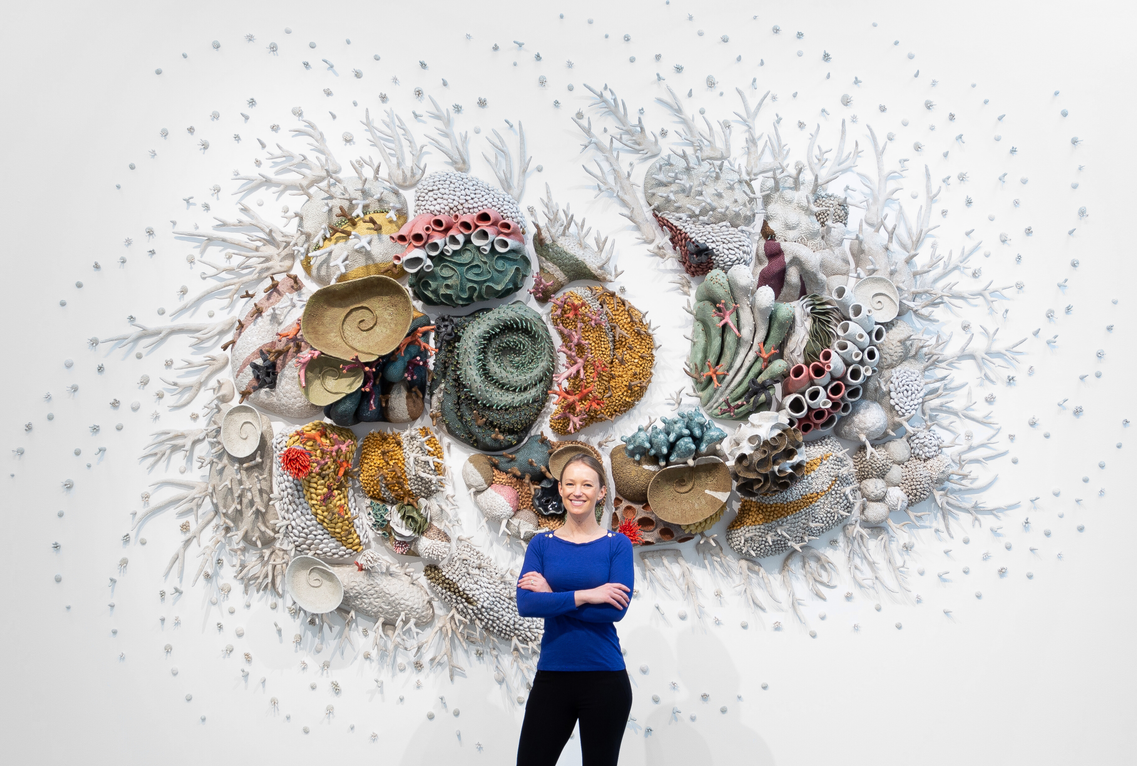 Image of artist Courtney Mattison standing in front of one of her works.