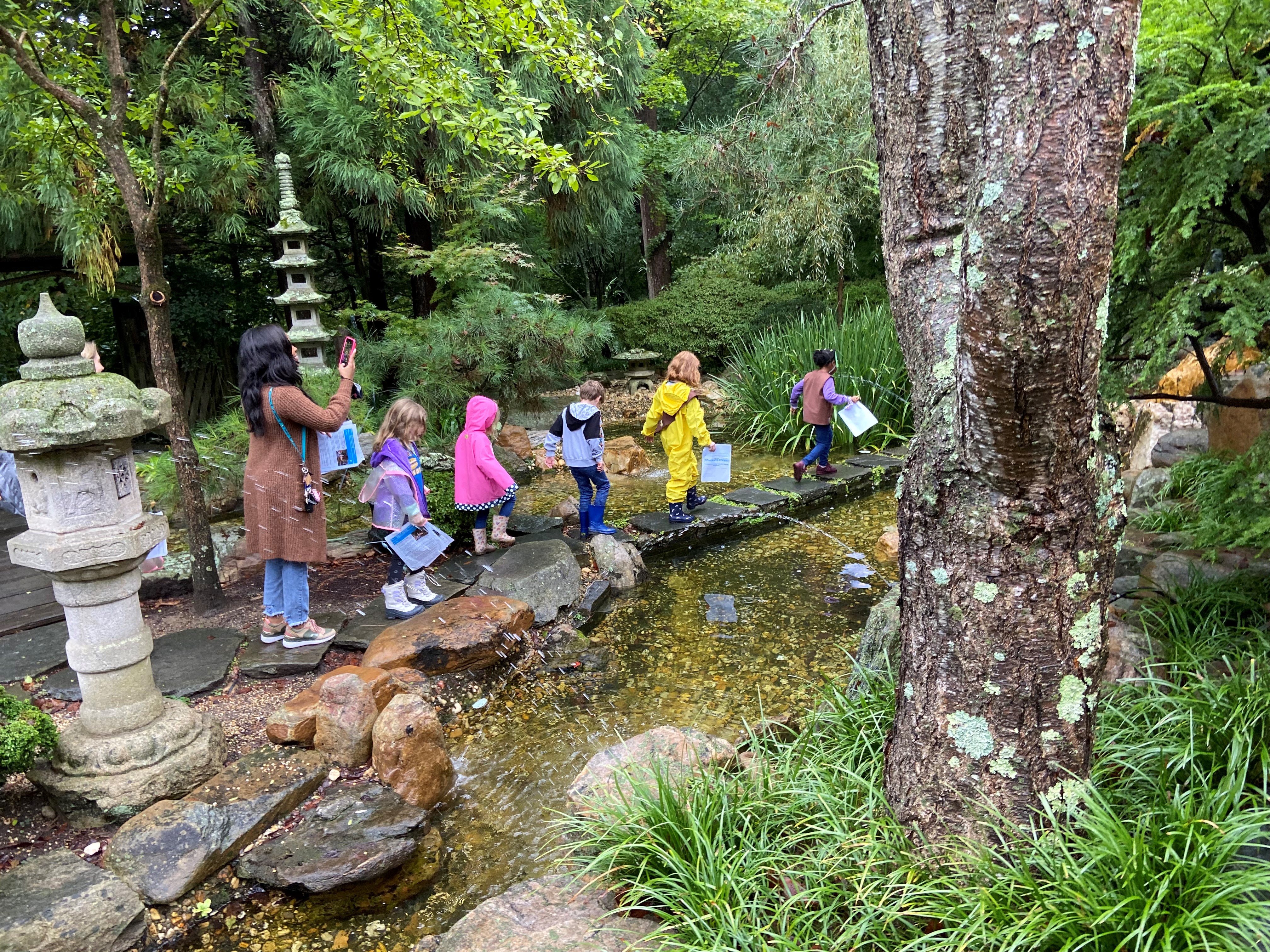 A Girl Scout troop walks across a stone bridge in Hillwood's Japanese-style garden.