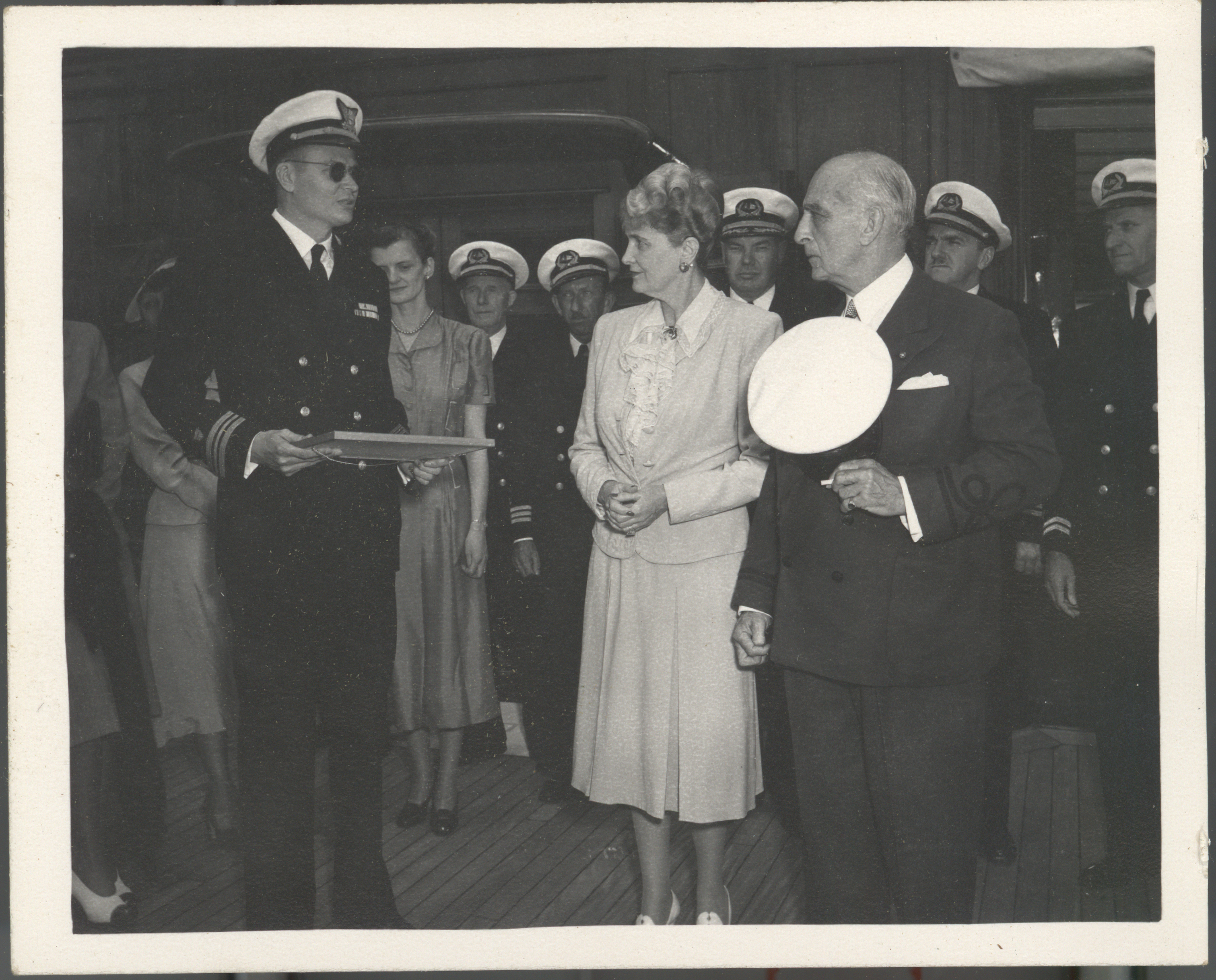 Black and white photo featuring Captain Skinner presenting a certificate to Marjorie Post and her husband, Joseph E. Davies.