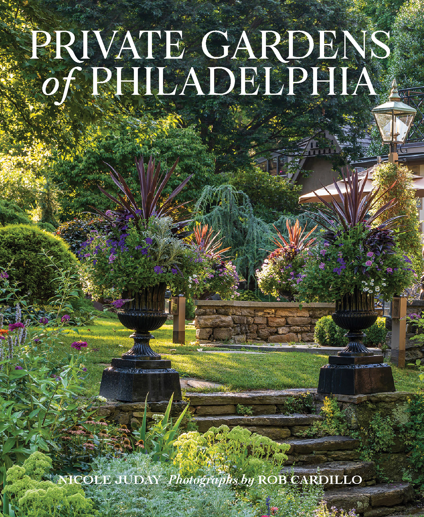 Cover of the book "Private Gardens of Philadelphia." It features a lush yard with many flowers and tropical plants with a home and lamppost in the background. 