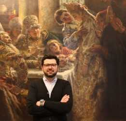 Photo of Wilfried Zeisler standing in front of Konstantin Makovsky's monumental painting The Boyar Wedding Feast