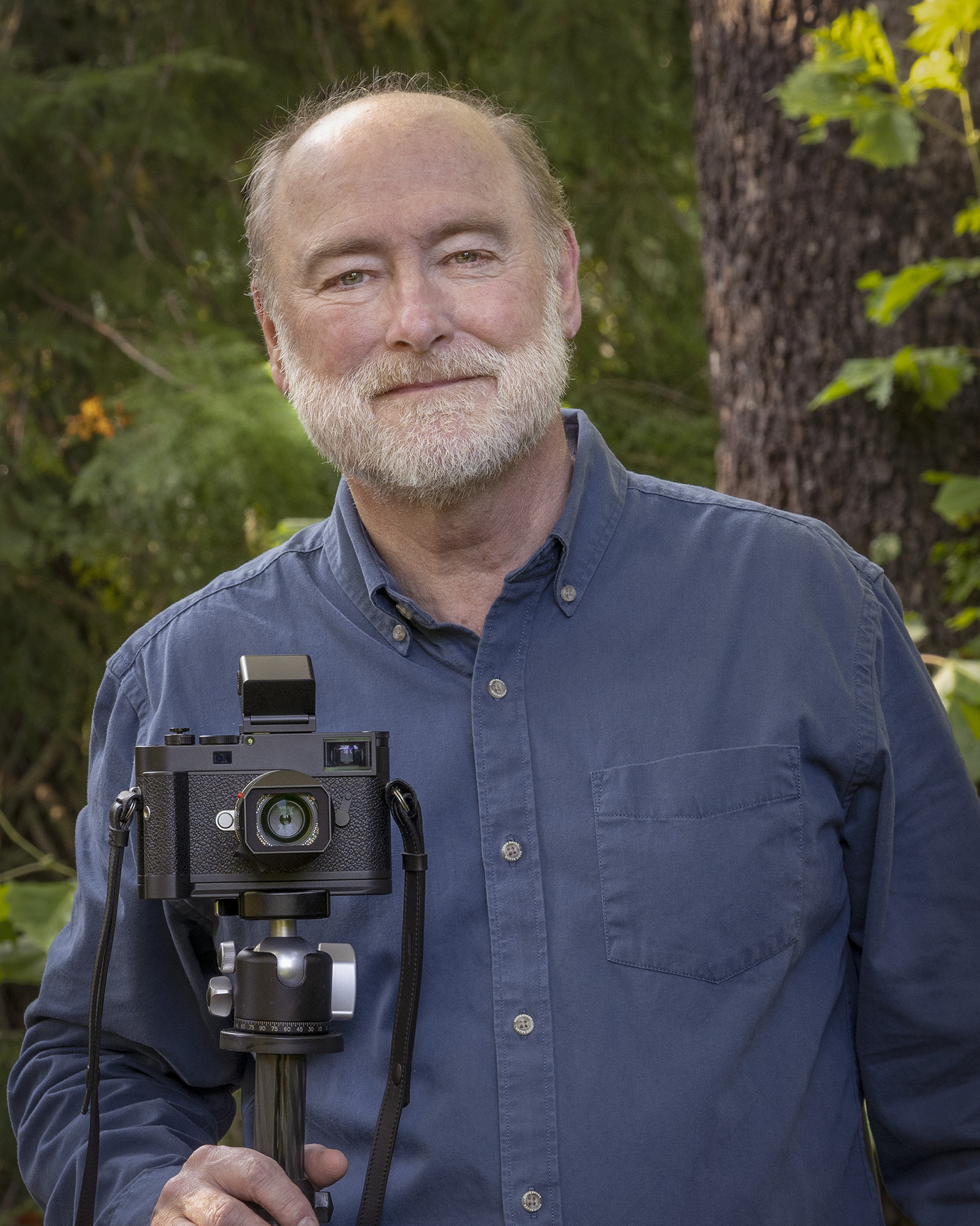 Image of Norman Barker, posing with a camera on a tripod.