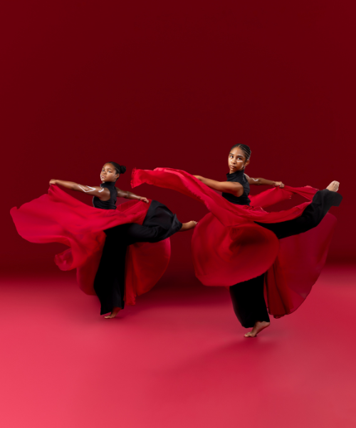 Image of two young dancers posing with red scarves wrapped around them.