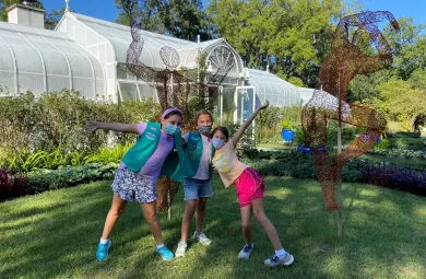 Girl Scouts pose in front of a wire statue by artist Kristine Mays displayed on the lawn in front of Hillwood's greenhouse.