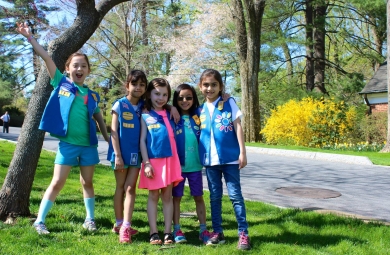 Five Daisy Girl Scouts gathered together and smiling outdoors in Hillwood's gardens