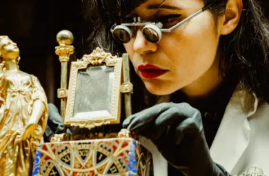 Image of Brittany Nico Cox working on an ornate clock. The image is close up, and she is wearing magnifying glasses.
