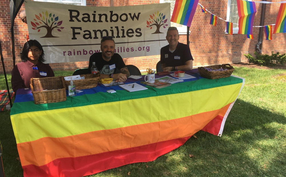 Rainbow Families staff and volunteers at table with rainbow tablecloth and Rainbow Families banner