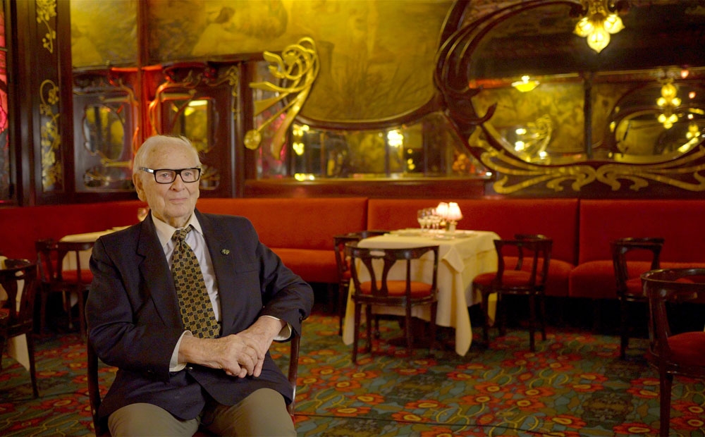 Pierre Cardin sits to the left in a theatrical room, during an interview for House of Cardin