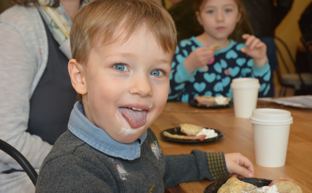 Young boy with light brown hair and blue eyes enjoying fluffy crepes