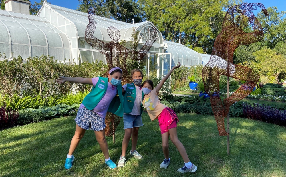 Girl Scouts pose in front of a wire statue by artist Kristine Mays displayed on the lawn in front of Hillwood's greenhouse.