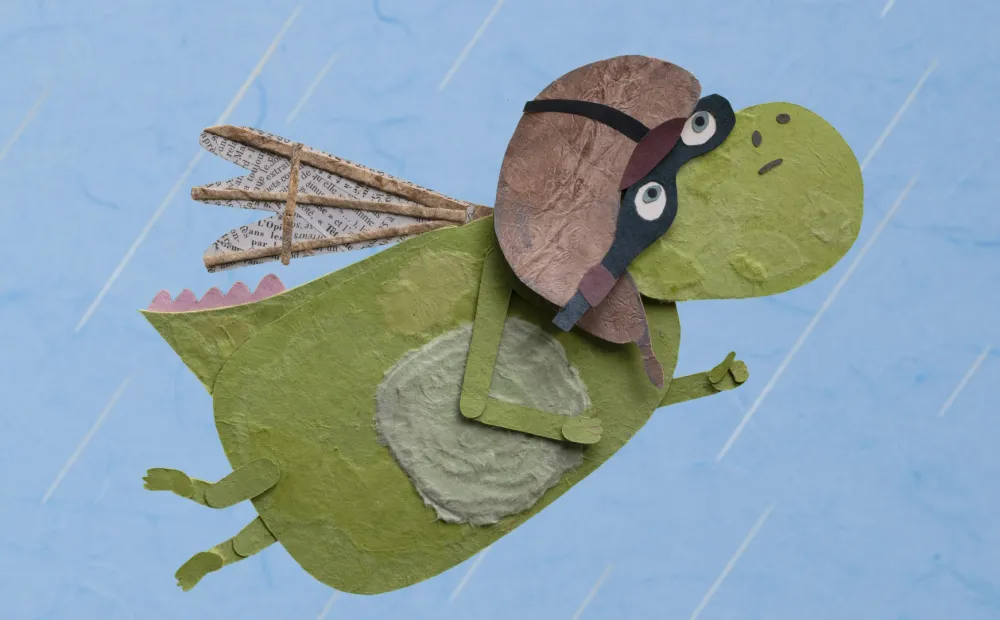 papercut illustration of a green dragon wearing a pilot helmet and goggles, flying across a blue sky