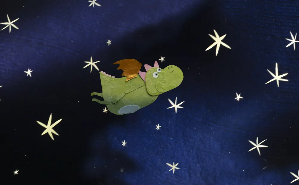 illustration of a friendly green dragon flying across a dark nighttime sky with twinkling stars