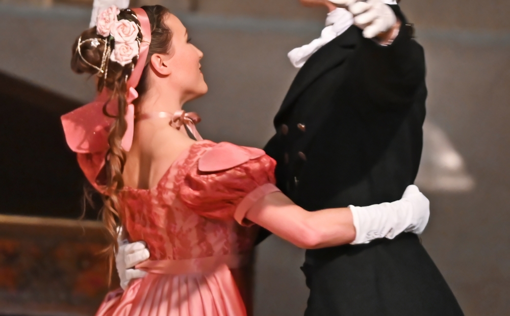 Image of two dancers, one with their arm wrapped around the other. 